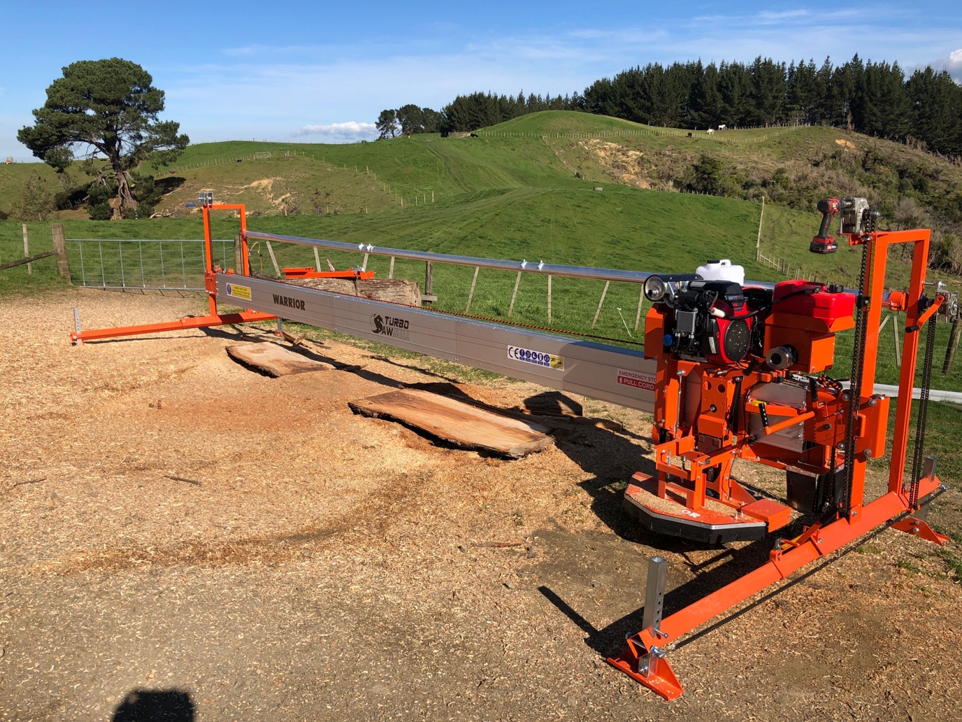 Portable Turbosawmill swing-blade sawmill set up around a log outdoors.